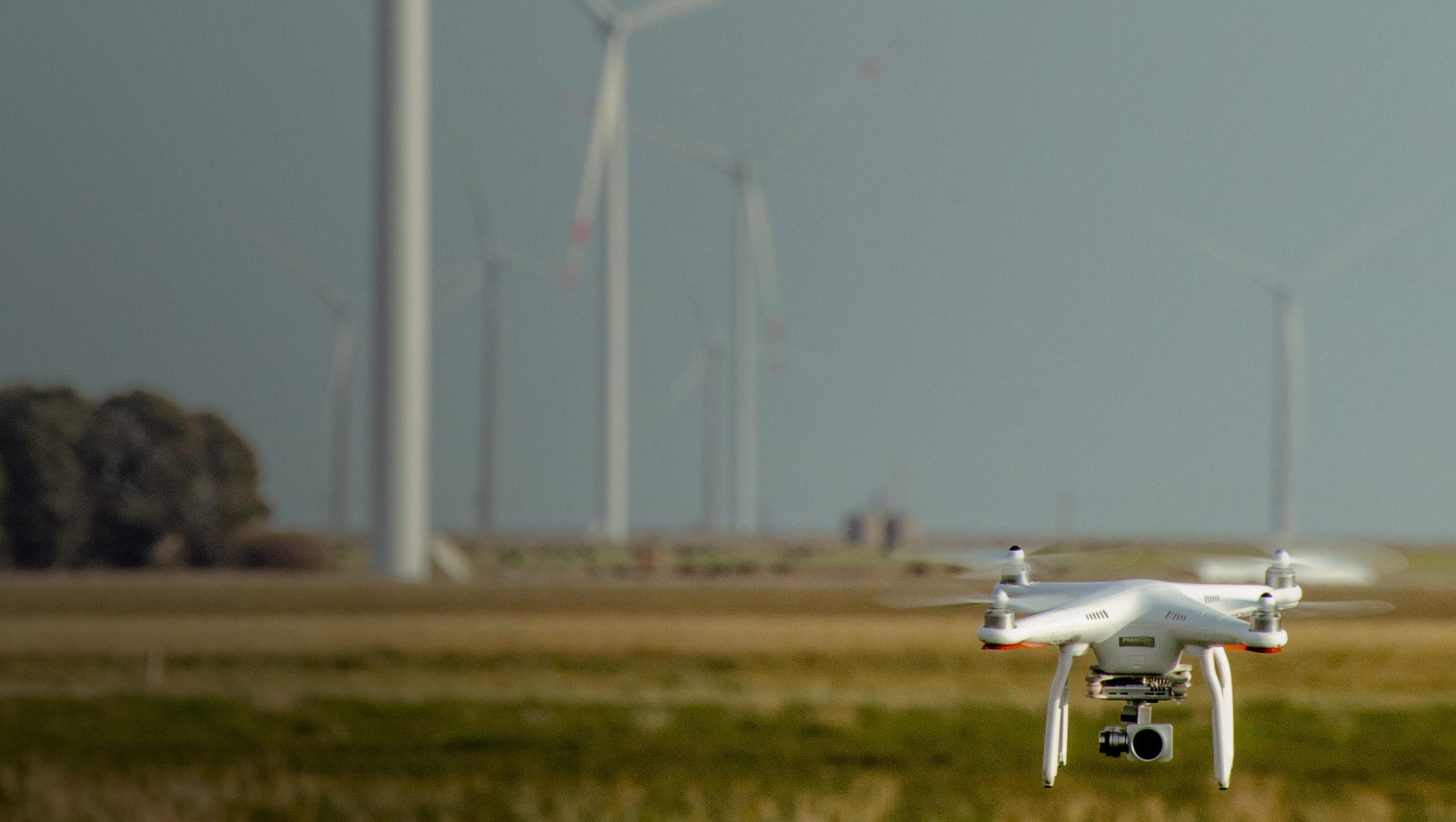 Photo d'un drone en vol devant des éoliennes